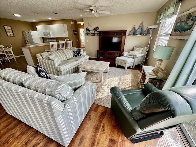 living room featuring dark wood-style floors, a ceiling fan, a textured ceiling, and recessed lighting