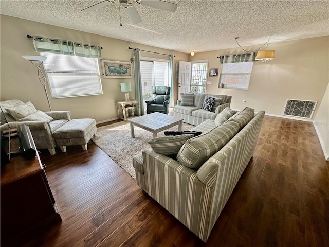 living room with visible vents, a textured ceiling, baseboards, and wood finished floors