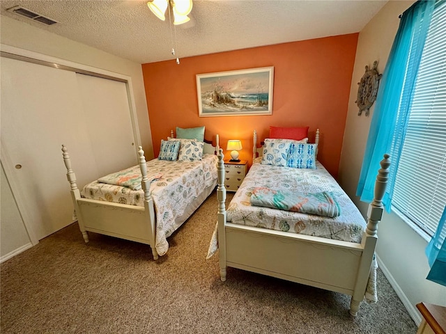 bedroom with carpet floors, a closet, visible vents, and a textured ceiling