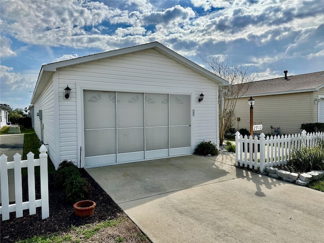 detached garage with fence and concrete driveway