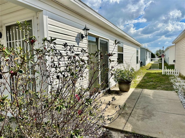 view of side of property featuring a yard, a patio, and fence