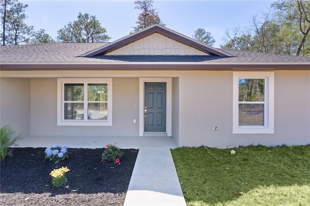 view of front of home featuring a shingled roof, a front lawn, and stucco siding