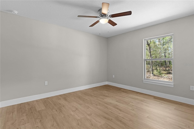 spare room with ceiling fan, light wood-style flooring, baseboards, and a textured ceiling