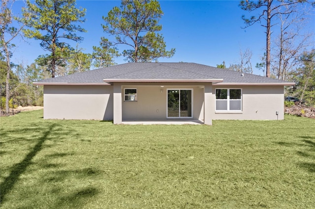 back of property featuring roof with shingles, a lawn, and stucco siding