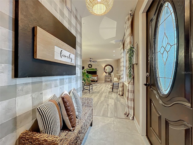 entryway featuring plenty of natural light, light tile patterned floors, a notable chandelier, and tile walls