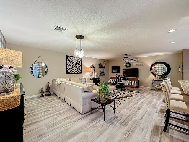 living area with baseboards, light wood-style flooring, visible vents, and a ceiling fan