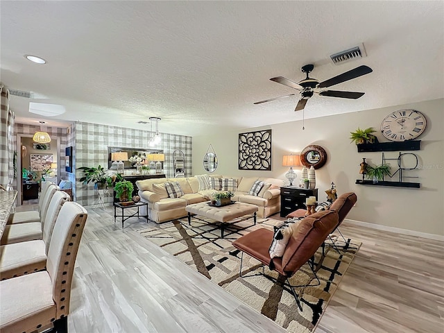living room featuring ceiling fan, baseboards, visible vents, and light wood-type flooring