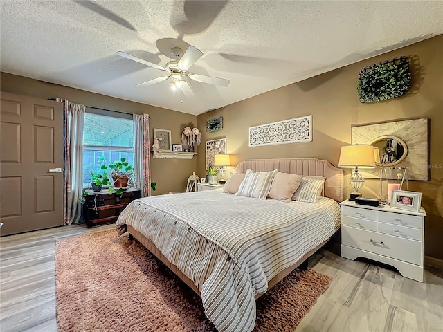 bedroom featuring light wood-type flooring, a textured ceiling, and a ceiling fan
