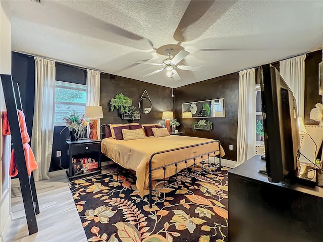 bedroom featuring a ceiling fan, a textured ceiling, and light wood-type flooring