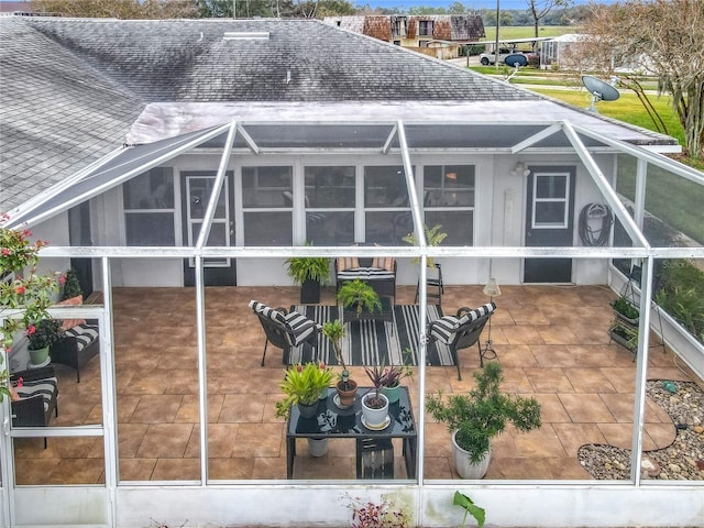 rear view of property featuring a lanai, roof with shingles, and a patio