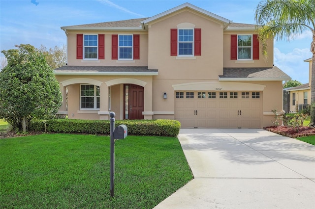 view of front of home featuring a garage, a front lawn, concrete driveway, and stucco siding