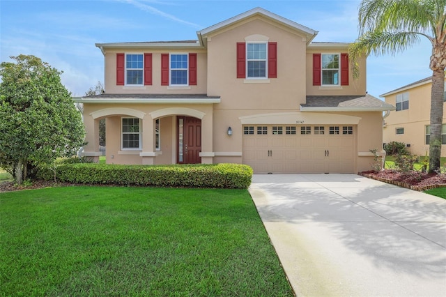 view of front of house with driveway, a garage, a front yard, and stucco siding