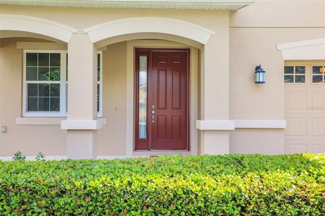 doorway to property with an attached garage and stucco siding