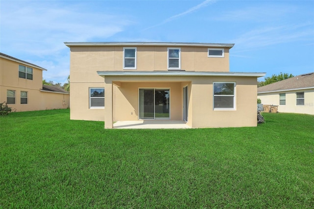 back of house featuring a lawn, a patio area, and stucco siding