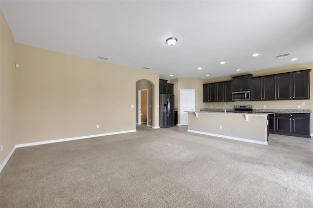 kitchen featuring arched walkways, stainless steel appliances, open floor plan, and visible vents