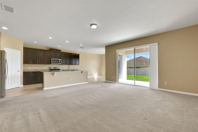 kitchen featuring appliances with stainless steel finishes, open floor plan, visible vents, and light carpet