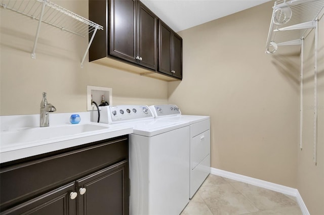 laundry room featuring light tile patterned floors, a sink, baseboards, independent washer and dryer, and cabinet space