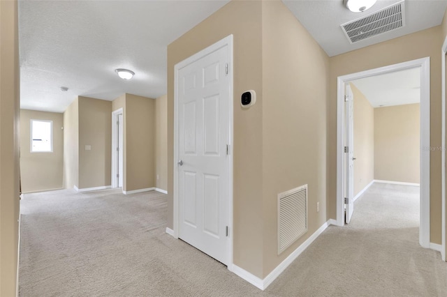 hall with carpet, visible vents, and baseboards