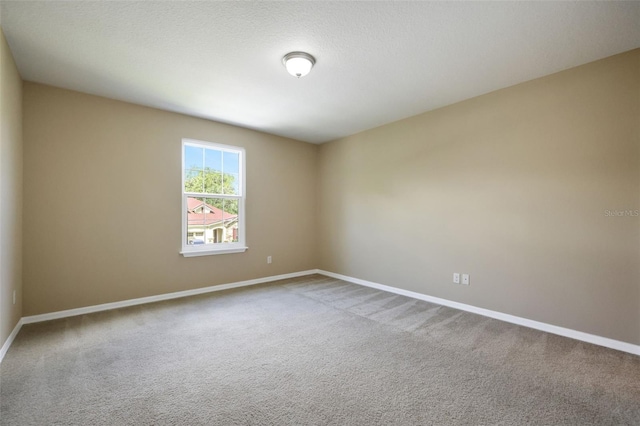 carpeted spare room with a textured ceiling and baseboards