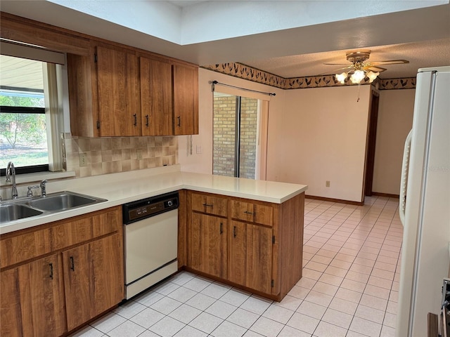 kitchen featuring light tile patterned floors, light countertops, a sink, white appliances, and a peninsula