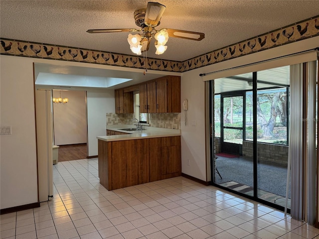 kitchen with a sink, a peninsula, light tile patterned floors, and light countertops