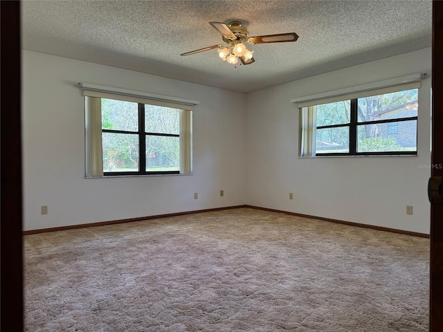 carpeted spare room with a ceiling fan, a textured ceiling, baseboards, and a wealth of natural light