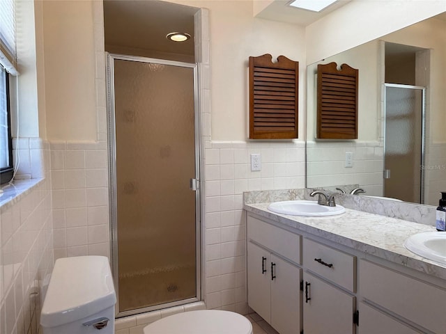 full bath with tile walls, double vanity, toilet, a sink, and a shower stall