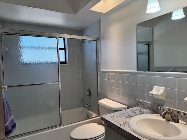 bathroom featuring toilet, vanity, tile walls, and enclosed tub / shower combo