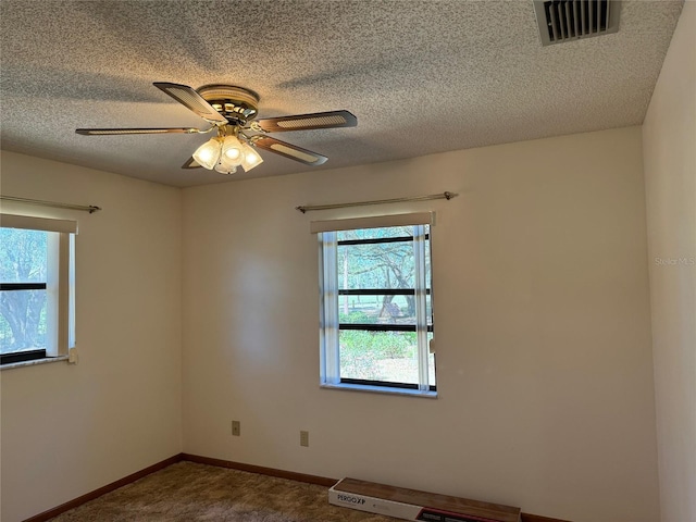 carpeted empty room with a ceiling fan, baseboards, visible vents, and a textured ceiling