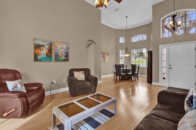 living area featuring arched walkways, baseboards, a notable chandelier, and hardwood / wood-style floors