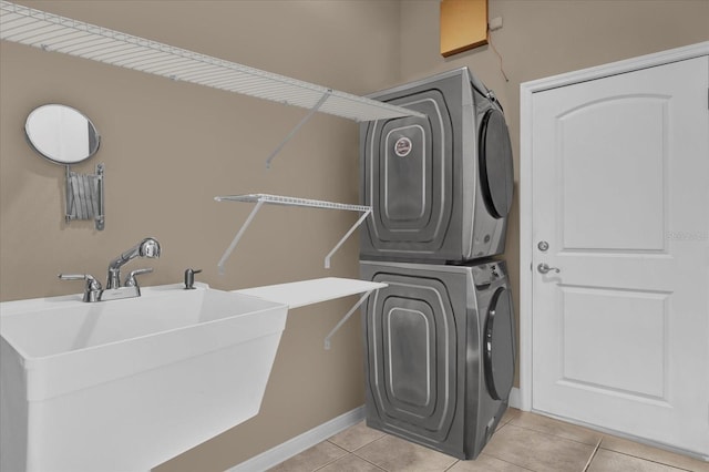 laundry room with light tile patterned floors, laundry area, stacked washing maching and dryer, and a sink