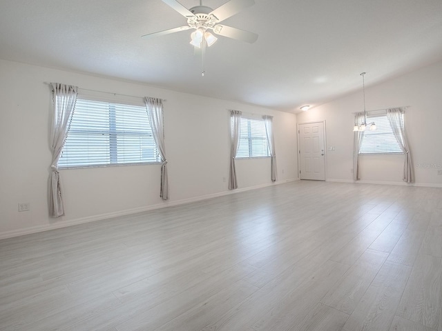 spare room with light wood-style floors, baseboards, vaulted ceiling, and ceiling fan with notable chandelier