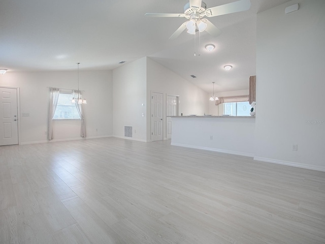 unfurnished living room featuring light wood finished floors, lofted ceiling, visible vents, baseboards, and ceiling fan with notable chandelier