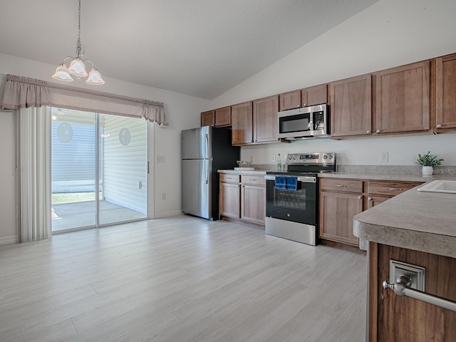 kitchen with light wood finished floors, stainless steel appliances, lofted ceiling, light countertops, and hanging light fixtures