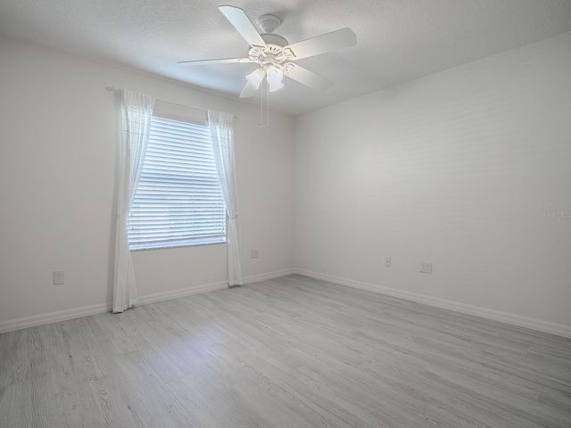 empty room with baseboards, ceiling fan, a textured ceiling, and light wood finished floors