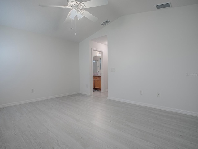 unfurnished room with lofted ceiling, light wood-type flooring, visible vents, and baseboards