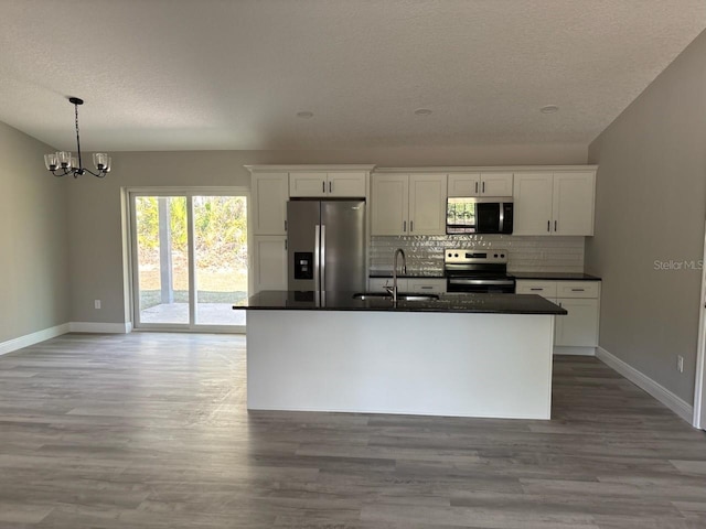 kitchen with appliances with stainless steel finishes, dark countertops, a sink, and white cabinets