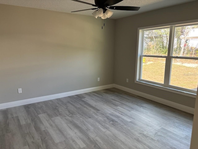 unfurnished room featuring a textured ceiling, wood finished floors, a ceiling fan, and baseboards