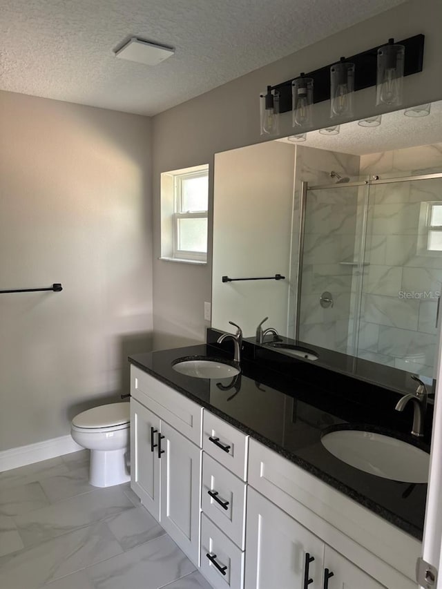 full bath featuring a stall shower, marble finish floor, a sink, and a textured ceiling