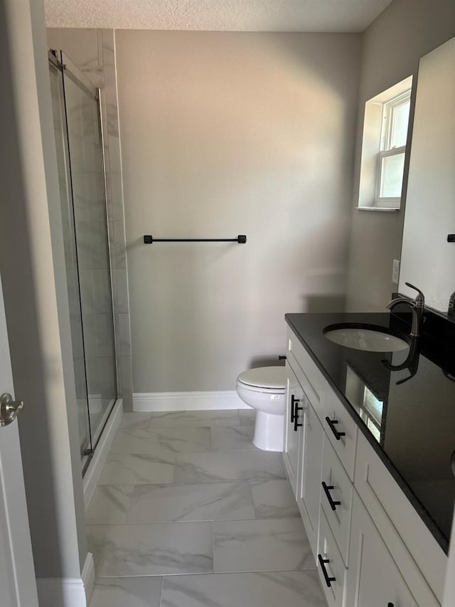 bathroom featuring marble finish floor, a stall shower, toilet, and baseboards