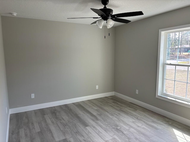 spare room with a ceiling fan, a textured ceiling, baseboards, and wood finished floors