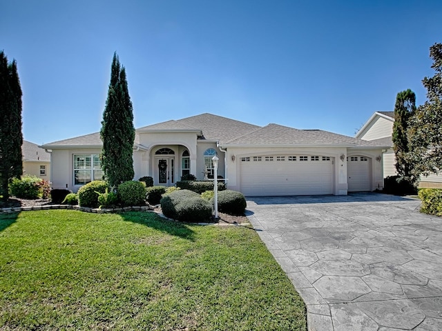 view of front facade with a garage, driveway, a front lawn, and stucco siding