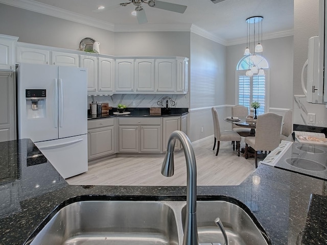 kitchen with ornamental molding, white appliances, white cabinets, and a sink