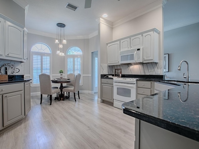 kitchen with white appliances, visible vents, light wood-style flooring, and backsplash