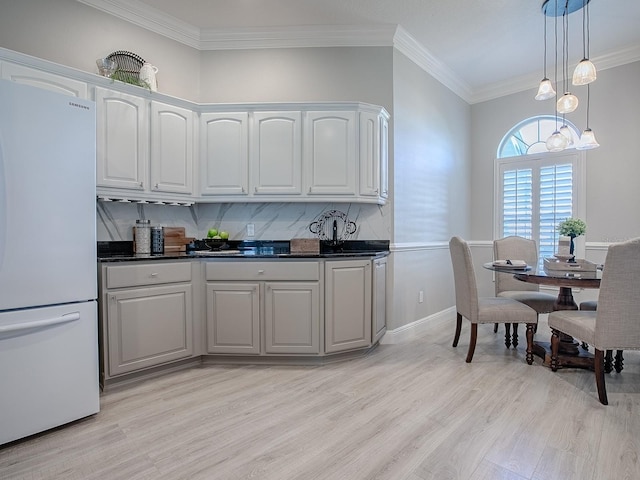 kitchen with decorative light fixtures, light wood-style flooring, ornamental molding, freestanding refrigerator, and white cabinetry