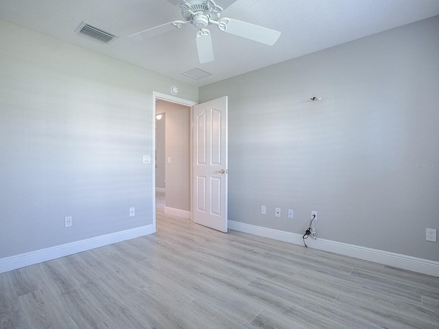 spare room with light wood-style flooring, a ceiling fan, visible vents, and baseboards