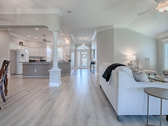 living area featuring crown molding, light wood finished floors, decorative columns, and a ceiling fan