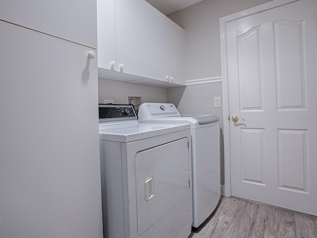 laundry area with light wood-type flooring, cabinet space, and washer and dryer