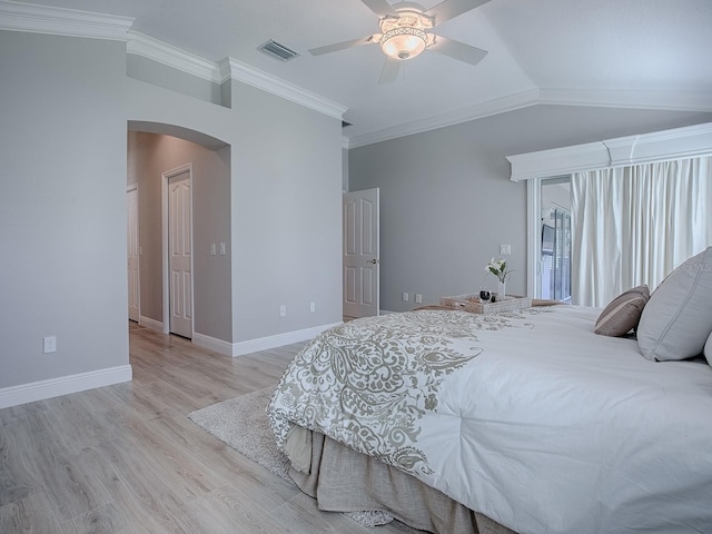 bedroom with visible vents, arched walkways, lofted ceiling, wood finished floors, and crown molding