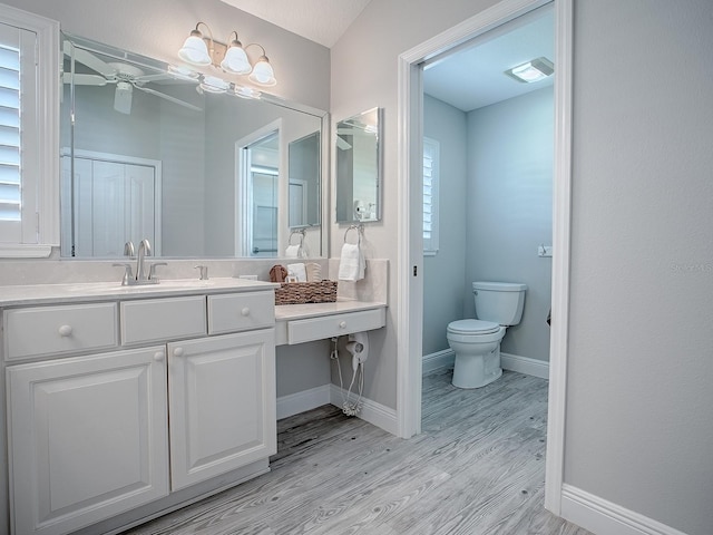 bathroom featuring toilet, a ceiling fan, vanity, wood finished floors, and baseboards